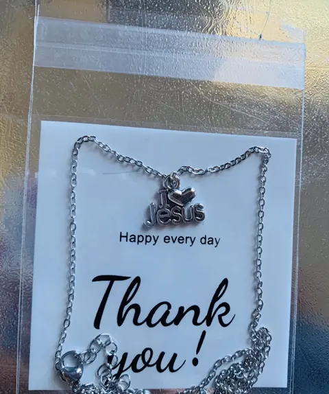 A silver chain necklace with an I heart Jesus charm on a card that says Happy every day, Thank you.