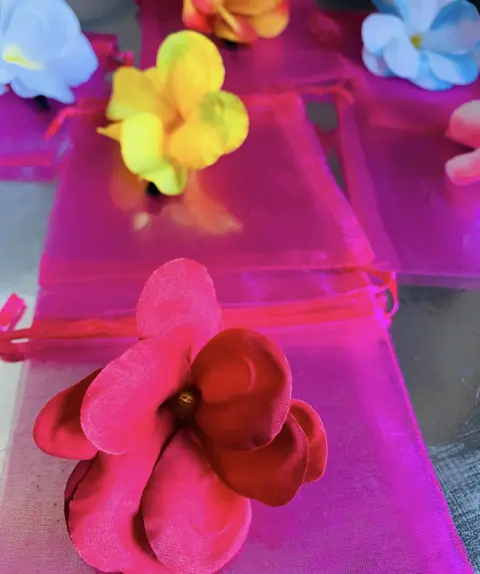 Flower hair clips in red, yellow and blue on pink organza pouches.